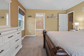 Une chambre à coucher avec un grand lit, une commode, une porte et un couloir menant à une autre pièce.