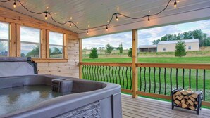 Un jacuzzi en una terraza de madera con vista a un campo de césped y edificios.