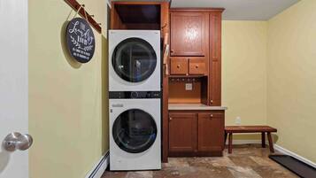 A laundry room with two washing machines, wooden cabinets, and a bench.