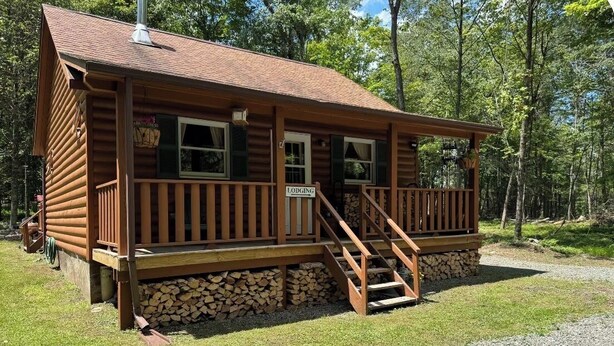 A wooden lodge with a porch and a staircase leading to the entrance. - Cozy Country Cabin (Long Eddy)
