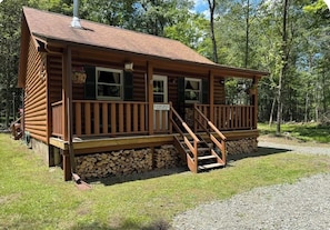 A wooden lodge with a porch and a staircase leading to the entrance.