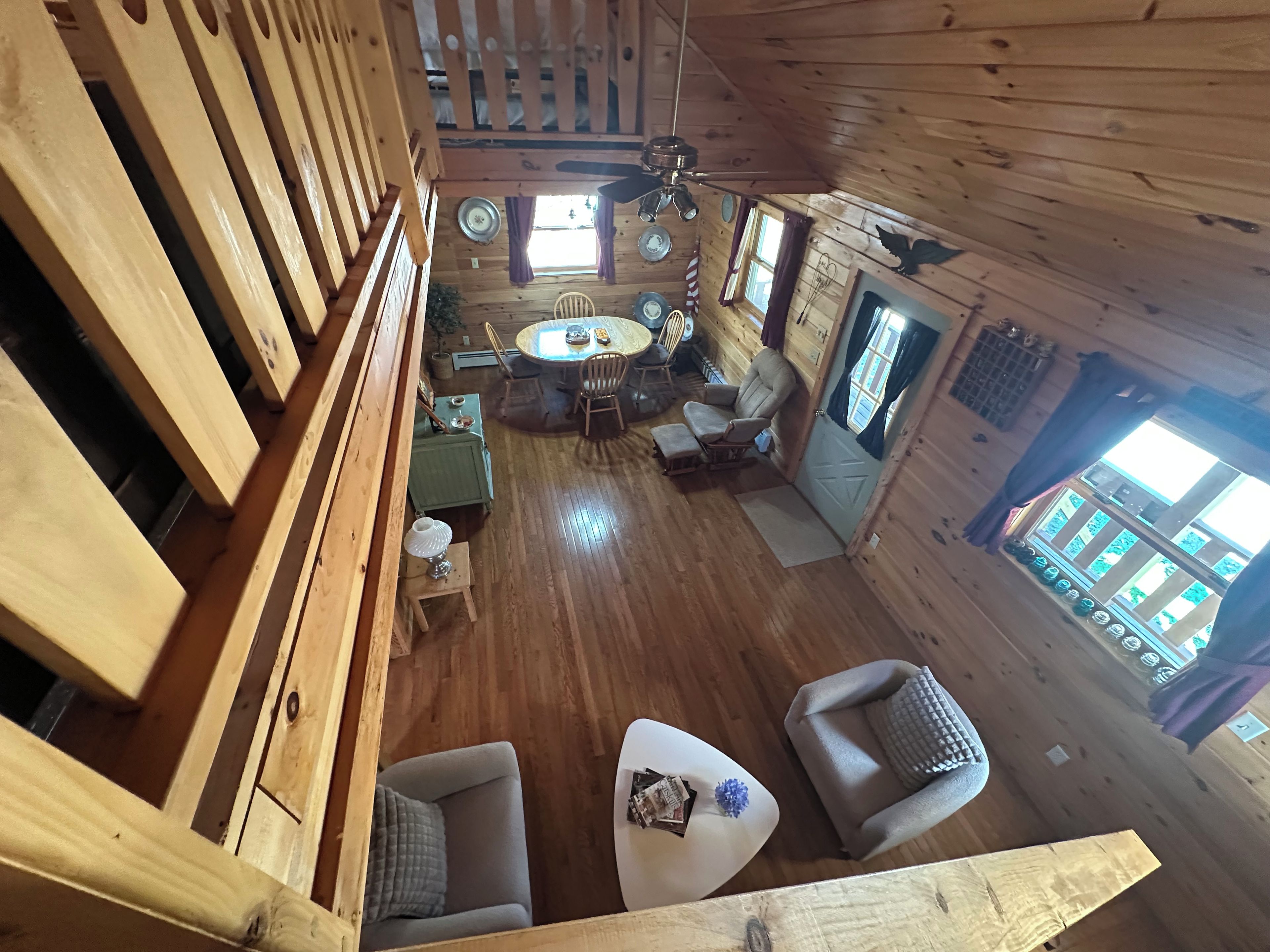 A wooden cabin interior with a dining area, seating, and a view through a window.