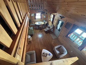 A wooden cabin interior with a dining area, seating, and a view through a window.