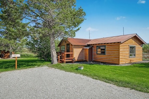 Eine Holzhütte mit einem Schotterweg und einem Schild, das 'Denny Creek Cabin Parking' anzeigt.