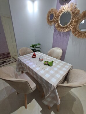 A dining area with a checkered tablecloth, four chairs, a vase with a plant, and decorative wall mirrors. - Vrbo Property (Tanger)