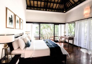 A bedroom with a bed, bedside table, lamp, and a view of the outdoors through large windows. - Ijen Resort (Banyuwangi)