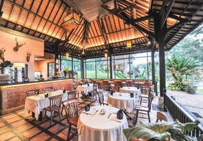 A restaurant with round tables, chairs, and a bar area. - Ijen Resort (Banyuwangi)