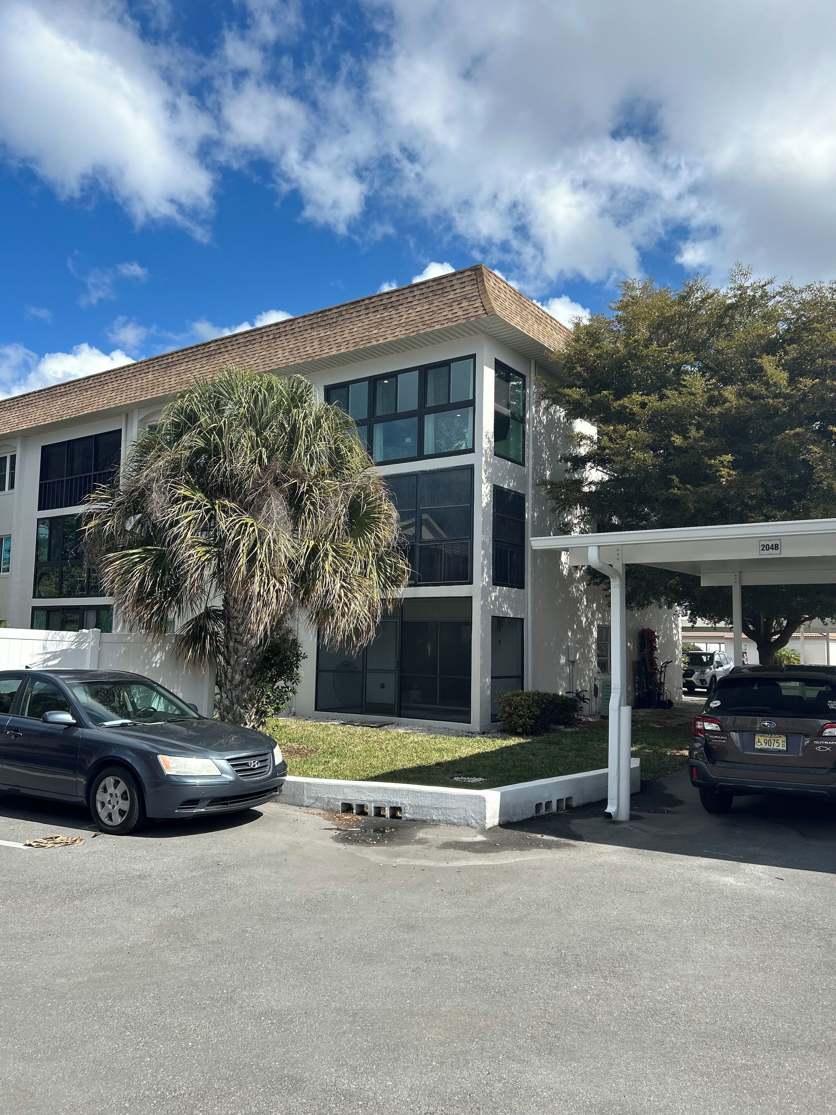 A modern building with a two-story structure, large windows, and a covered parking area.
