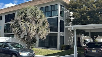 A modern building with a two-story structure, large windows, and a covered parking area.