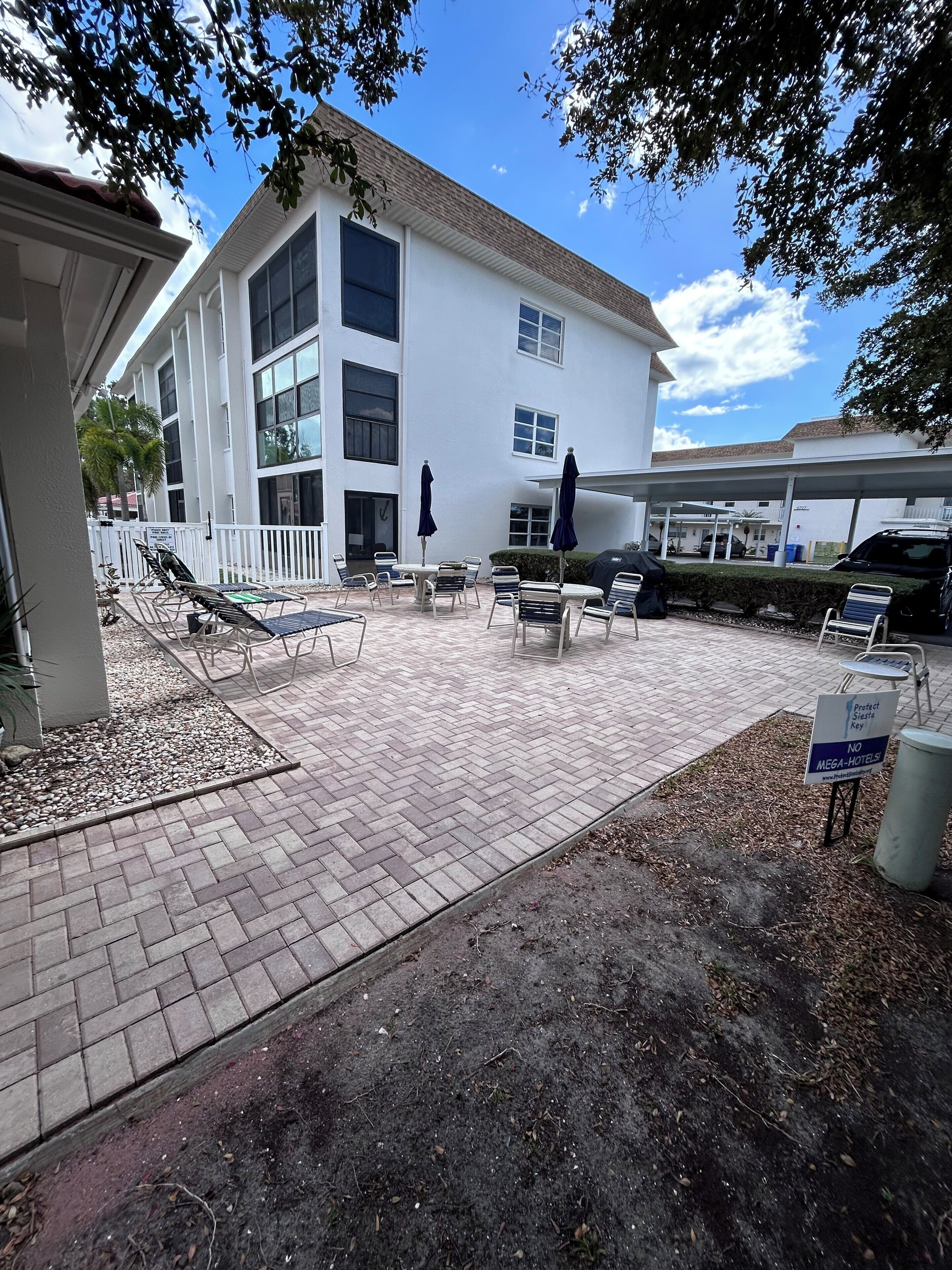 A hotel courtyard with outdoor seating, a covered area, and a building with multiple windows.
