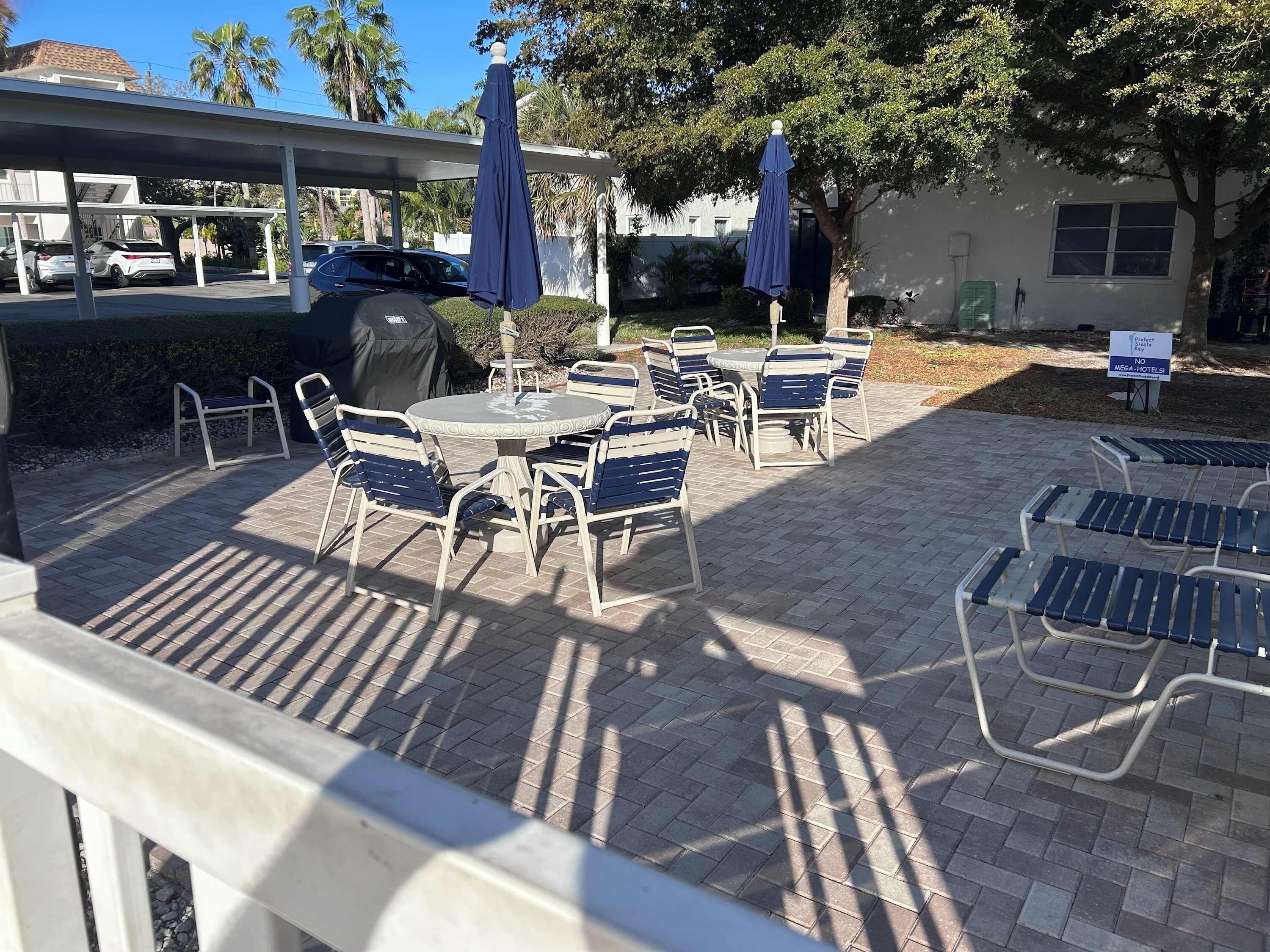 An outdoor patio area with tables and chairs, umbrellas, and a covered seating area.