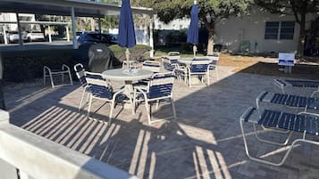 An outdoor patio area with tables and chairs, umbrellas, and a covered seating area.