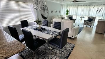A modern dining area with a large table, chairs, and a patterned rug.