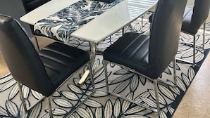 Un comedor con una mesa, sillas y un tapete decorativo.