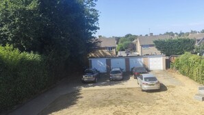 Ein Wohngebiet mit einer Garage, parkenden Autos und blauem Himmel.
