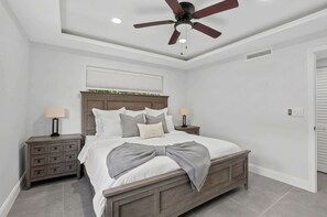 A bedroom with a bed, nightstands, a ceiling fan, and a window with blinds. - Coveside Hideaway 2 & Coastal Getaway (Deerfield Beach)