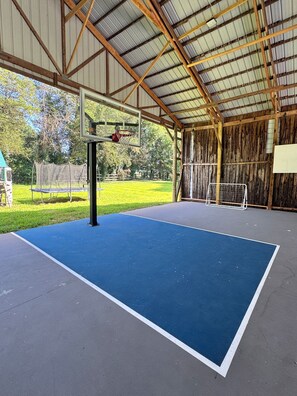 An indoor basketball court with a blue floor, a basketball hoop, and a net.