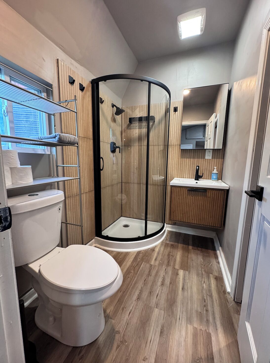 A modern bathroom with a glass-enclosed shower, a toilet, and a vanity with a mirror.