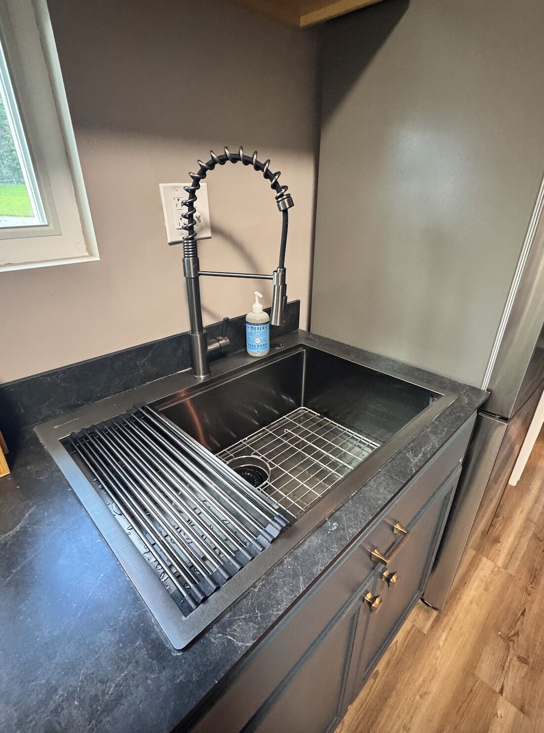 A kitchen with a stainless steel sink, a soap dispenser, and a modern faucet.