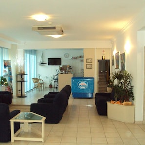 A living room with a sofa set, a coffee table, and a television mounted on the wall. - Canasta (Riccione)