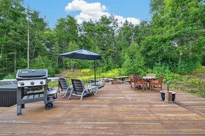 A wooden deck with a grill, lounge chairs, and a table with chairs. - 3BR Bethel retreat with patio, fire pit, WiFi, grill and parking. (Bethel)