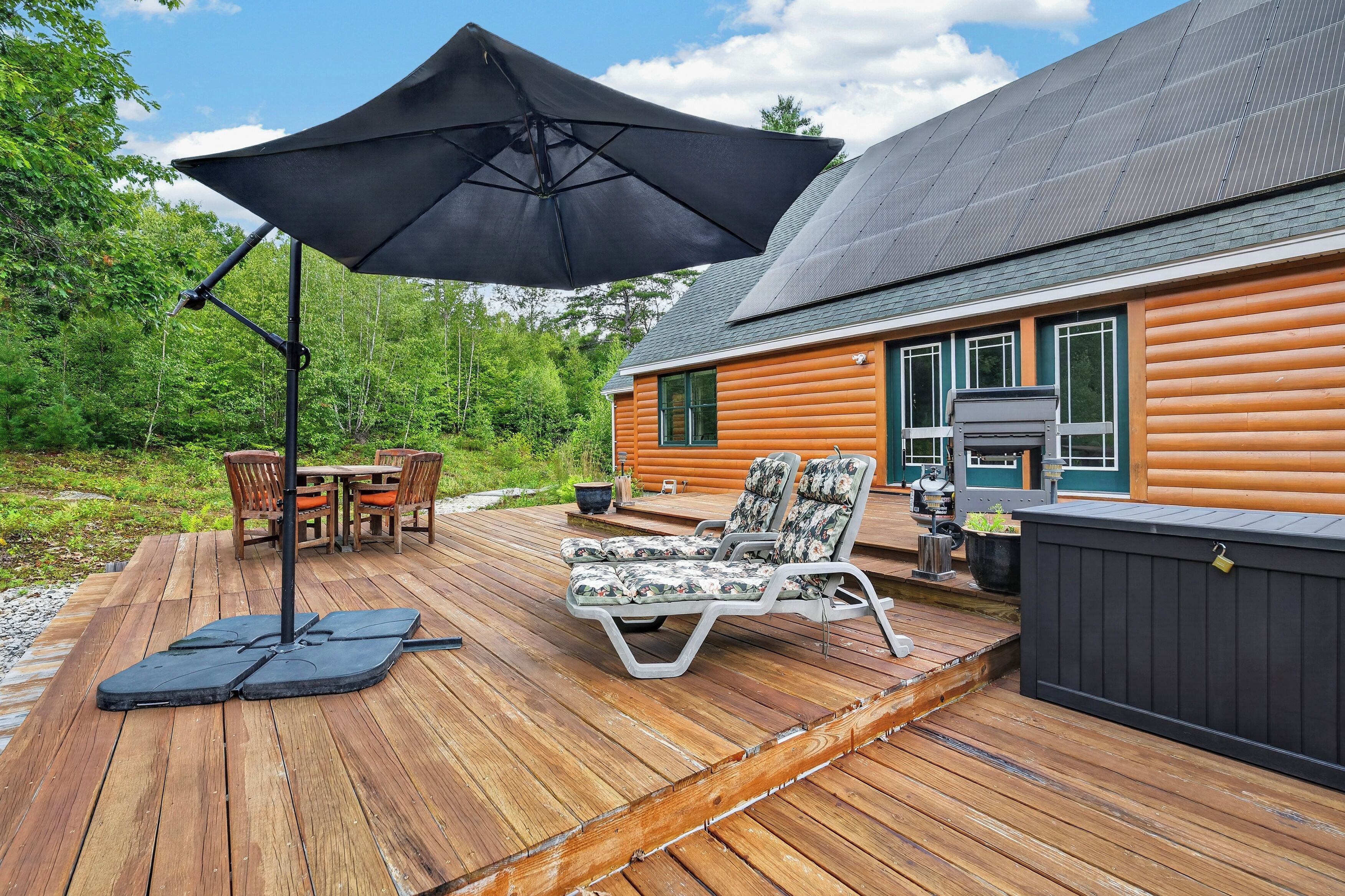 Una terraza de madera con mobiliario exterior, una sombrilla y un jacuzzi.