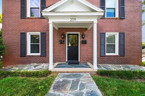 A brick house with a black front door, numbered 209, and a stone pathway leading to the entrance. - Downtown Days, Mountain Ways near Lake James (Morganton)