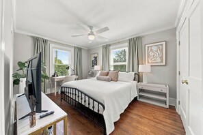 A bedroom with a bed, a desk, a television, and a ceiling fan. - Downtown Days, Mountain Ways near Lake James (Morganton)