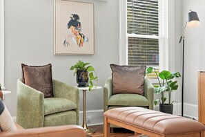 A living room with two green armchairs, a bench, a painting, and a window with blinds. - Downtown Days, Mountain Ways near Lake James (Morganton)