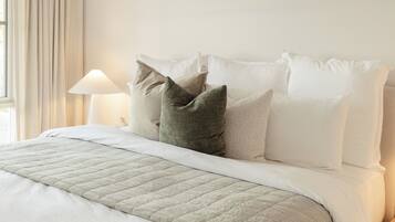 A neatly made bed with a quilted bedspread and a lamp on a bedside table.