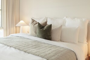 A neatly made bed with a quilted bedspread and a lamp on a bedside table.