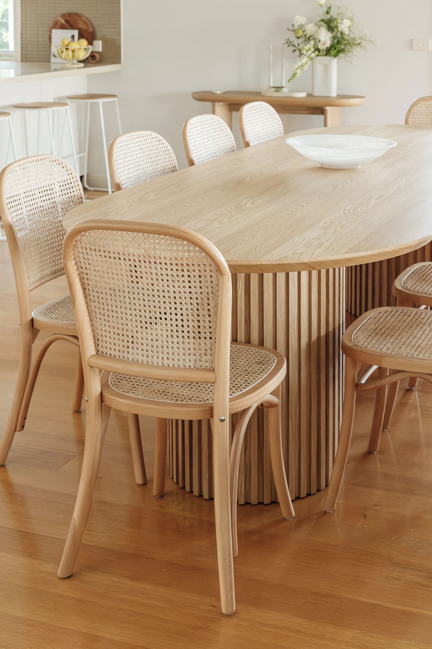 Un espace repas avec une grande table en bois entourée de six chaises en osier.