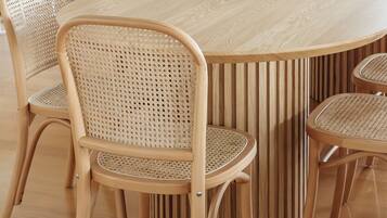 Un espace repas avec une grande table en bois entourée de six chaises en osier.