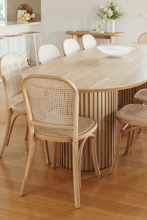 Un comedor con una gran mesa de madera rodeada por seis sillas de mimbre.