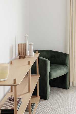 A room with a wooden desk, a chessboard, a green sofa, and a white vase. - Yarra Valley Lemon Grove Stay | Fireplace, Mountain Views, Sleeps 8 (Seville)