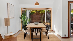 Ein Essbereich mit Holztisch und -stühlen, einer Hängelampe und Blick auf einen Garten durch eine Glastür.