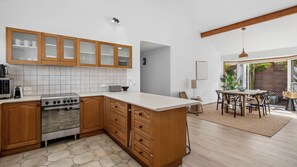 A modern kitchen with wooden cabinets, a stove, and a dining area with a table and chairs.