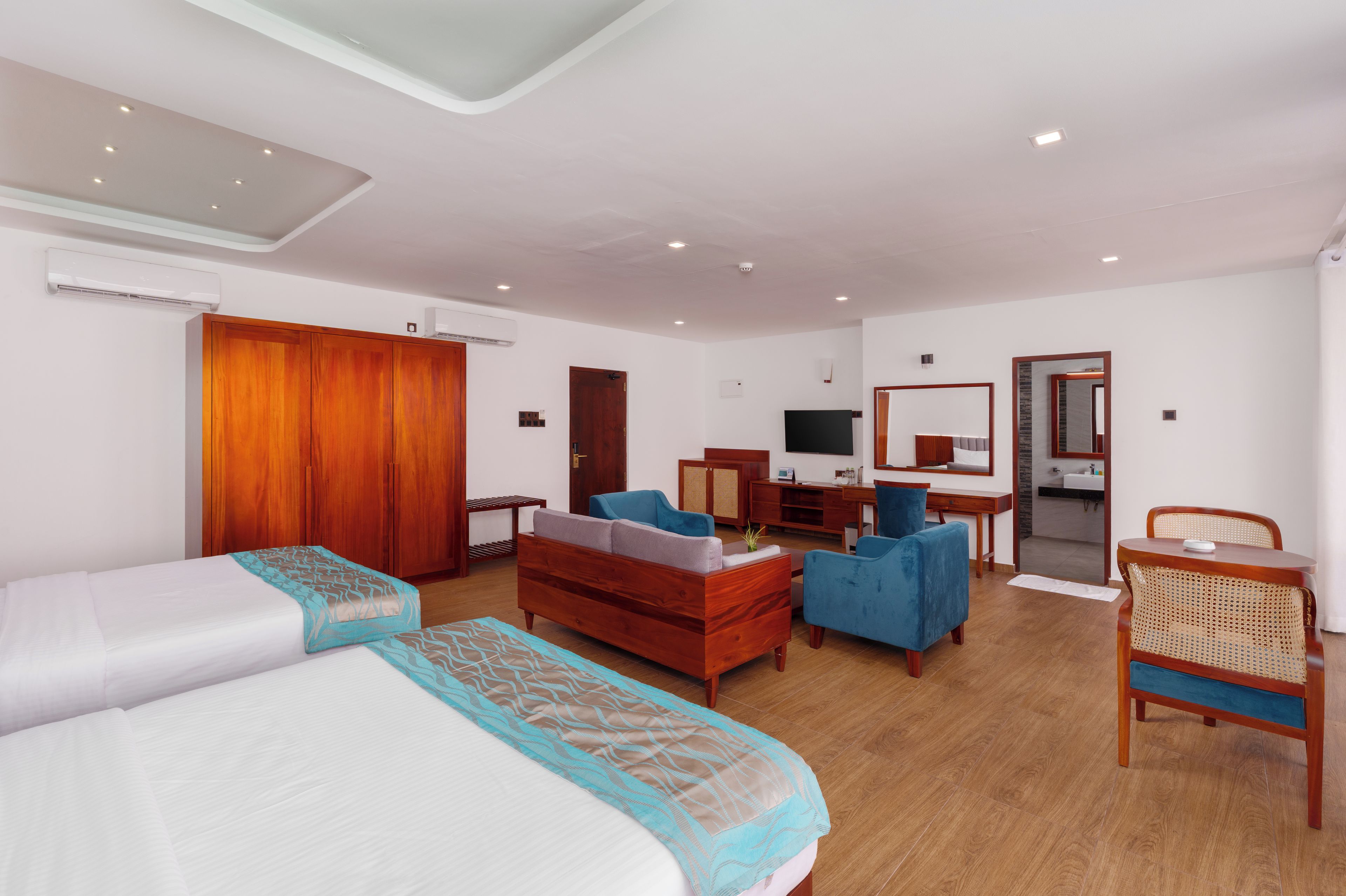 A hotel room with a bed, a desk, a chair, a TV, and a wardrobe.