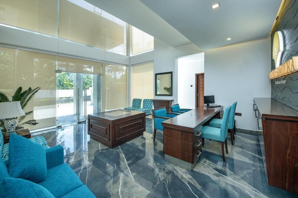 Una habitación amplia con un gran ventanal, un escritorio de madera, un sofá y una zona de comedor.