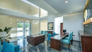 A spacious room with a large window, a wooden desk, a sofa, and a dining area. - Grand Samudra Hotel (Tangalle)