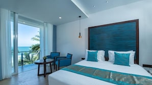 A hotel room with a large bed, a balcony with a view of the ocean, and a seating area with chairs. - Grand Samudra Hotel (Tangalle)