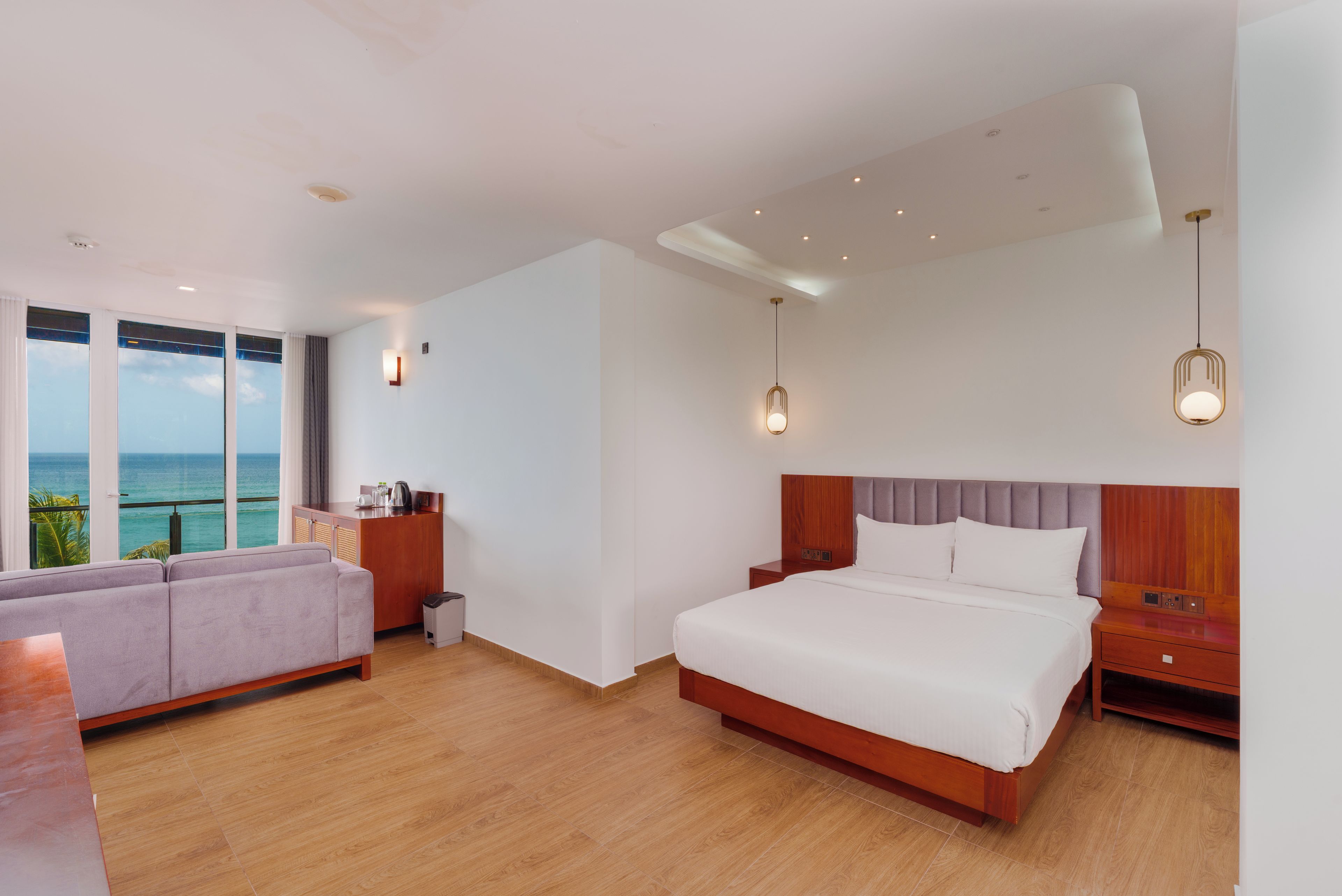 A modern hotel room with a large bed, a seating area, and a view of the ocean.