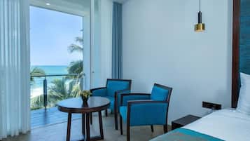 A hotel room with a bed, a table with chairs, and a view of the ocean.