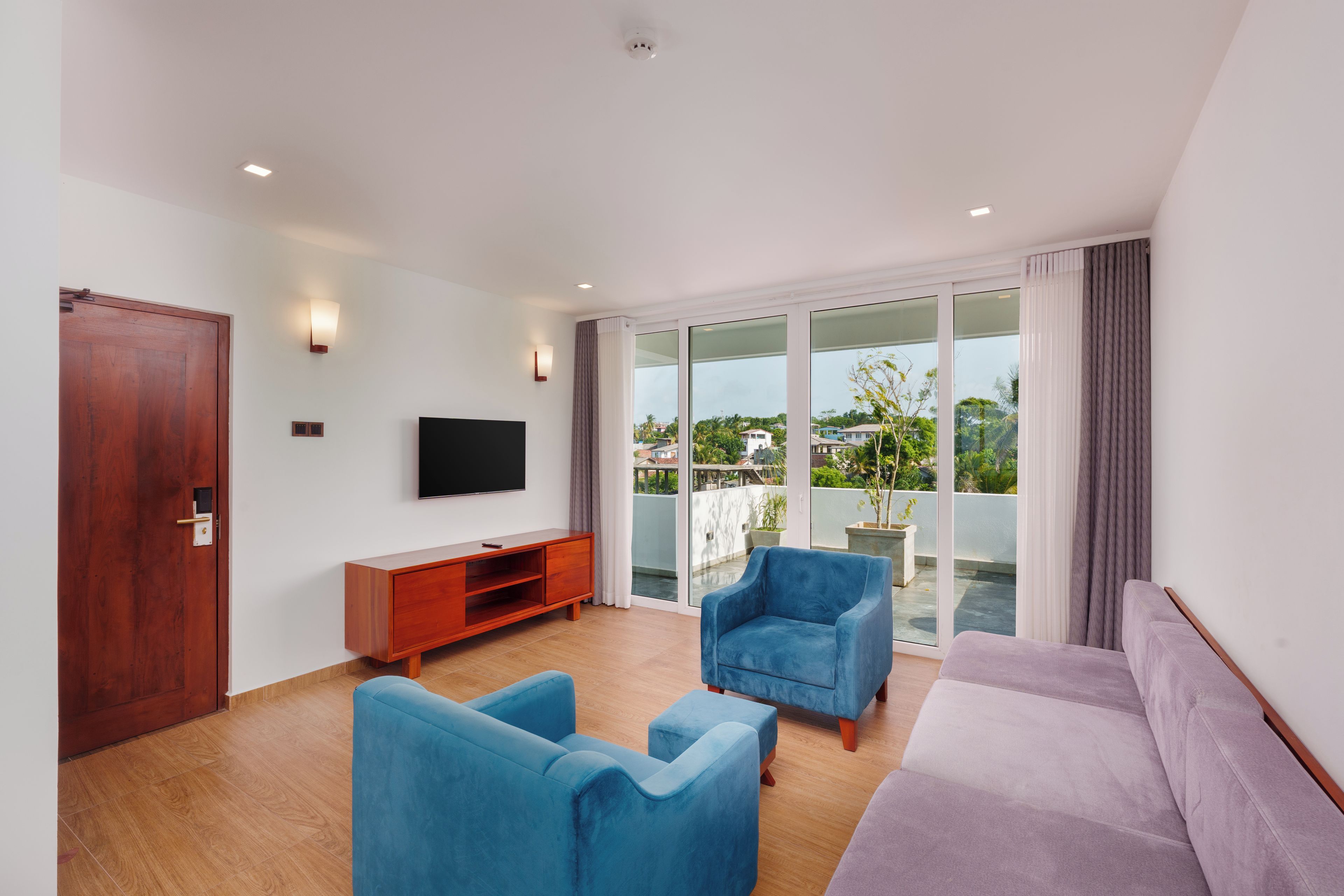 Una sala de estar moderna con un televisor de pantalla plana, un mueble de madera, un sofá y un sillón azul.