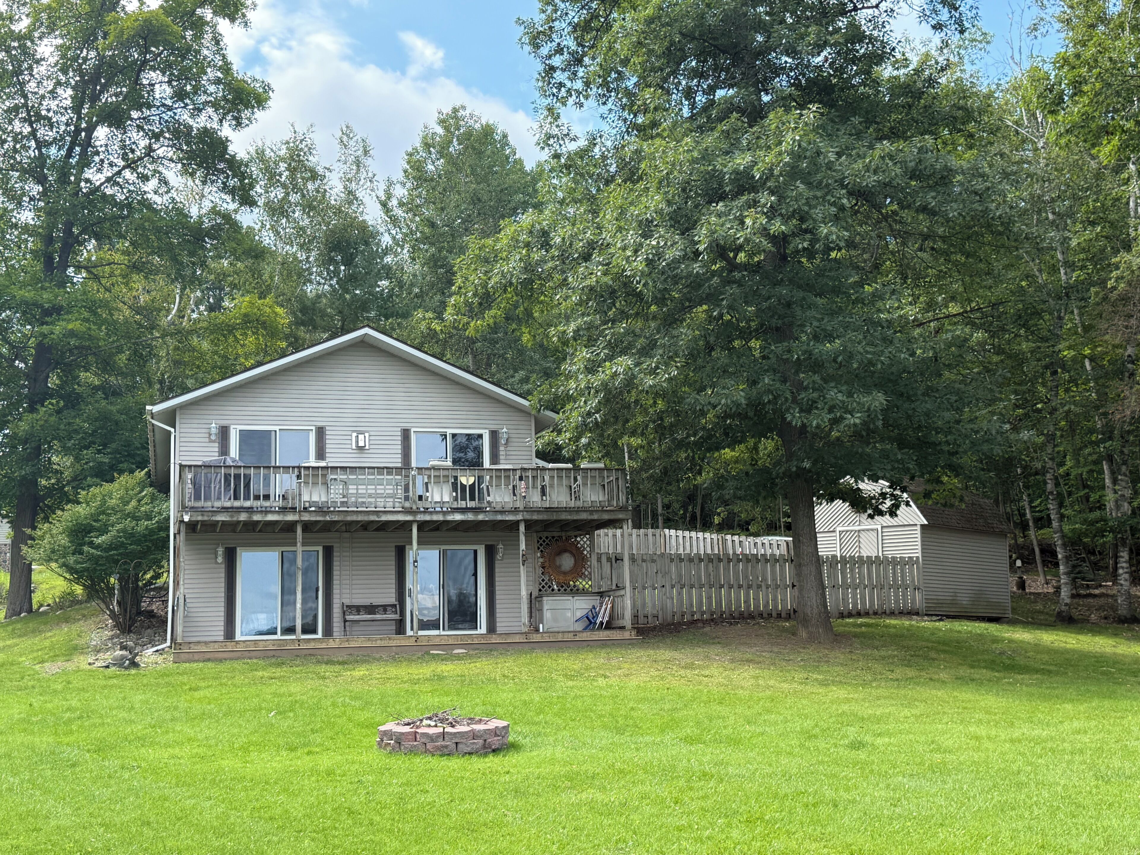 A two-story house with a balcony, a fenced yard, and a fire pit.