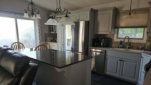 Una cocina moderna con una isla central, electrodomésticos de acero inoxidable e iluminación colgante.