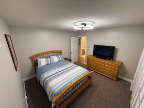 A bedroom with a bed, a television on a dresser, and a ceiling fan. - Sage Lake Paradise (Hale)