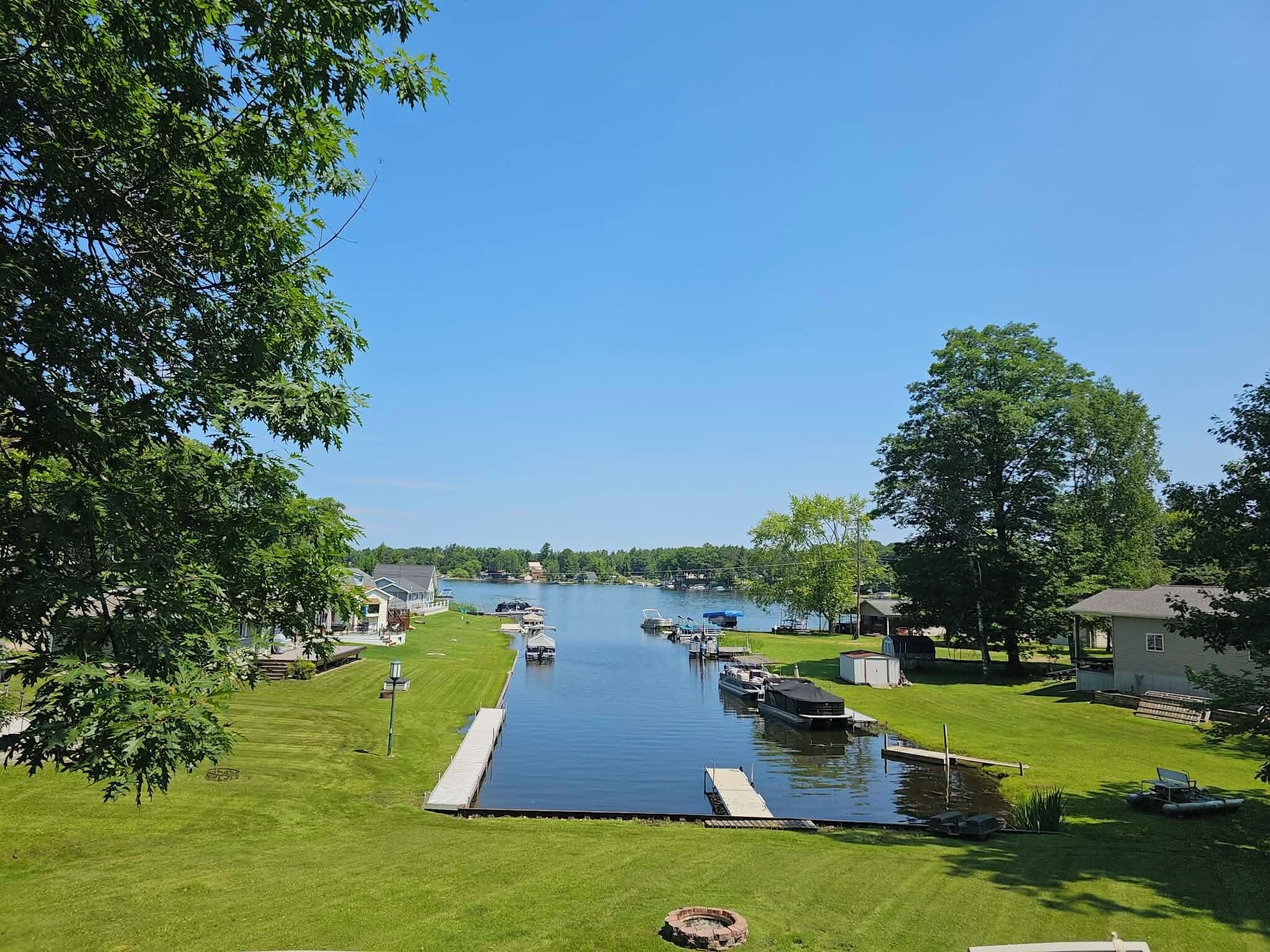A marina with boats docked, a grassy area, and a clear sky.