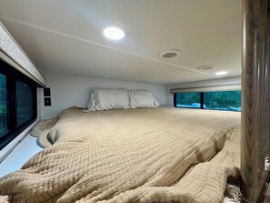Une chambre avec un grand lit, une fenêtre et un luminaire au plafond.