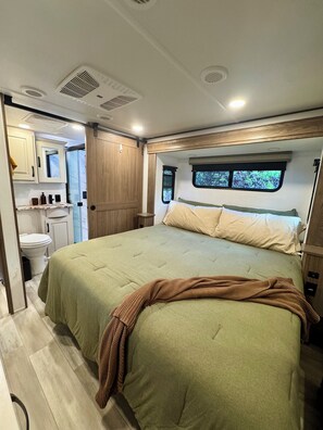 Een slaapkamer met een bed, een raam en een badkamer met toilet en wastafel.